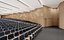 Elegante sala de conferências com painéis de madeira curvos e assentos em níveis.